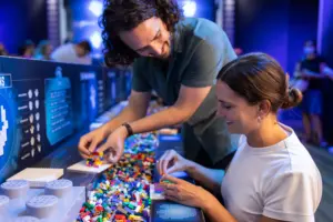 Nainen rakentamassa LEGOilla miehen kanssa LEGO® Jurassic World -tapahtumassa.